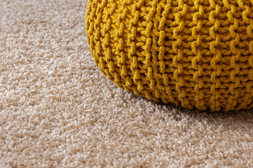 Yellow knitted bag on a beige carpet.
